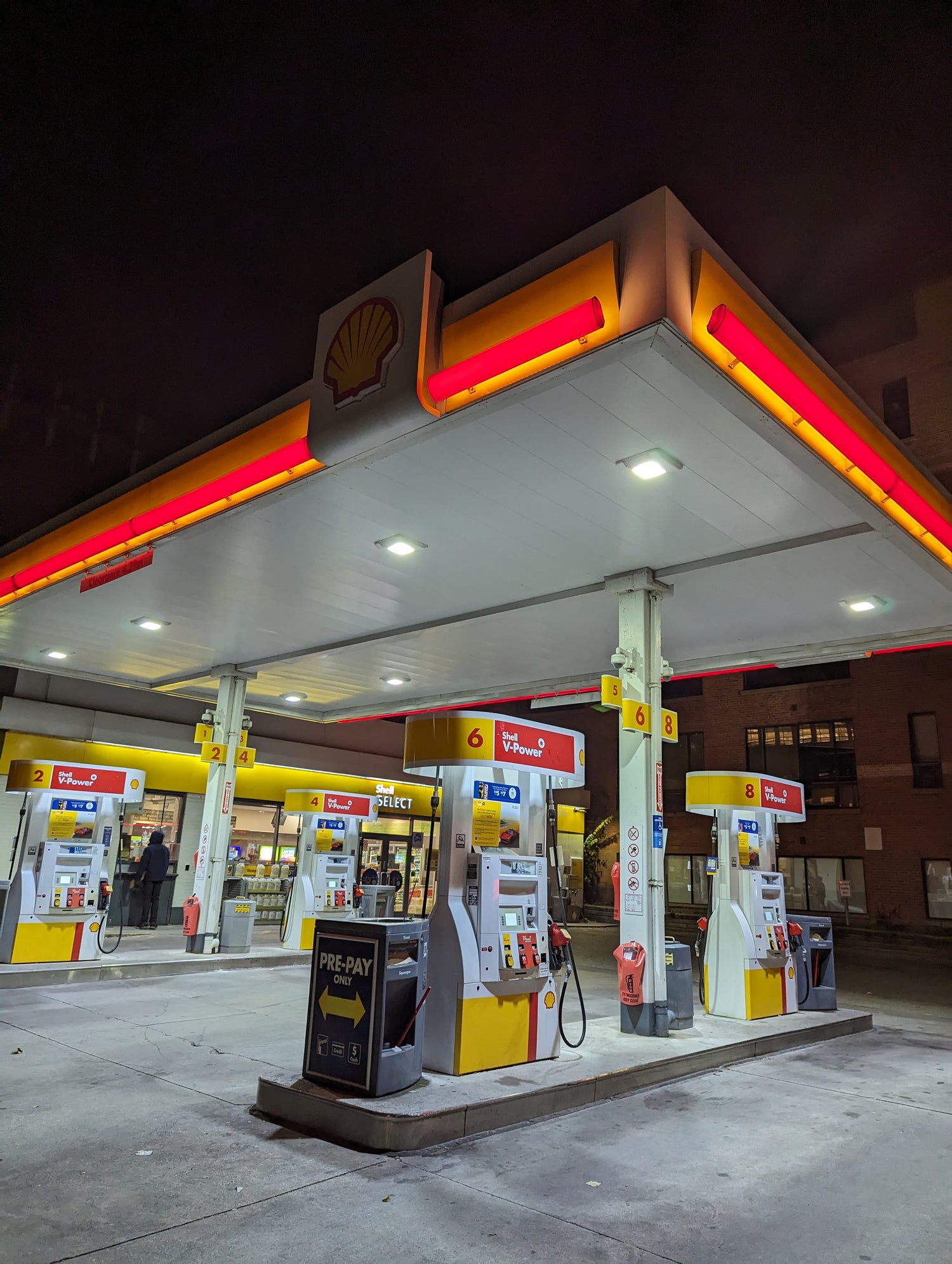 A high-visibility urban Shell gas station forecourt featuring modern fuel dispensers,  clean island layouts and Gorrie RCP products. Gorrie RCP provides the high-performance merchandising and facility equipment that maintains a premium retail brand image in city centers.